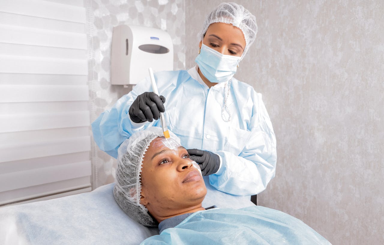 A beautician applies a treatment to a woman's face in a spa, focusing on skincare.