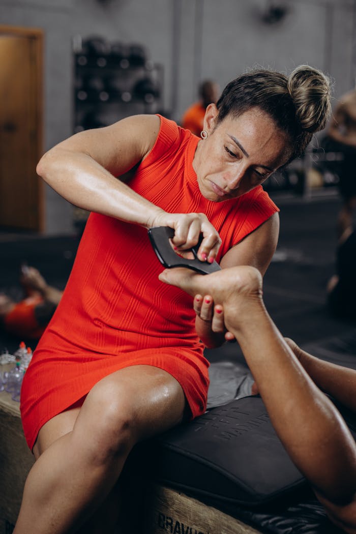 Professional foot massage therapy session showing a woman in a red dress massaging a foot.